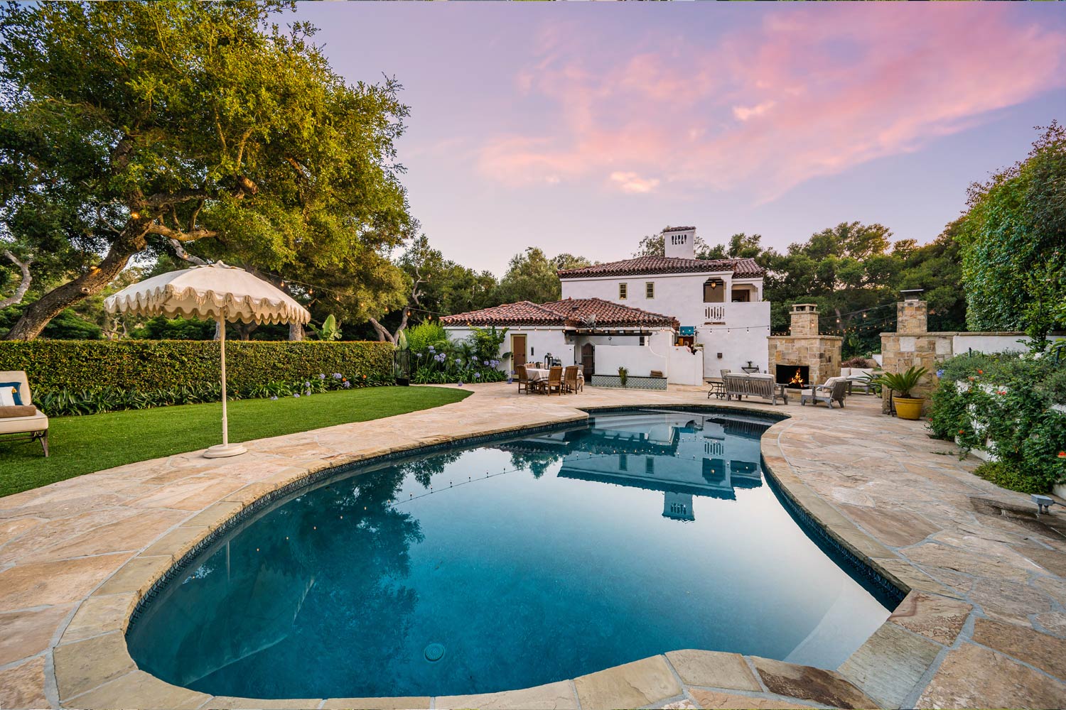 atardecer con casa lujosa y pisccina con una sombrilla a un lado